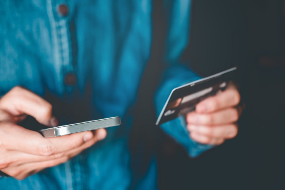 Person holding a bank card and mobile phone